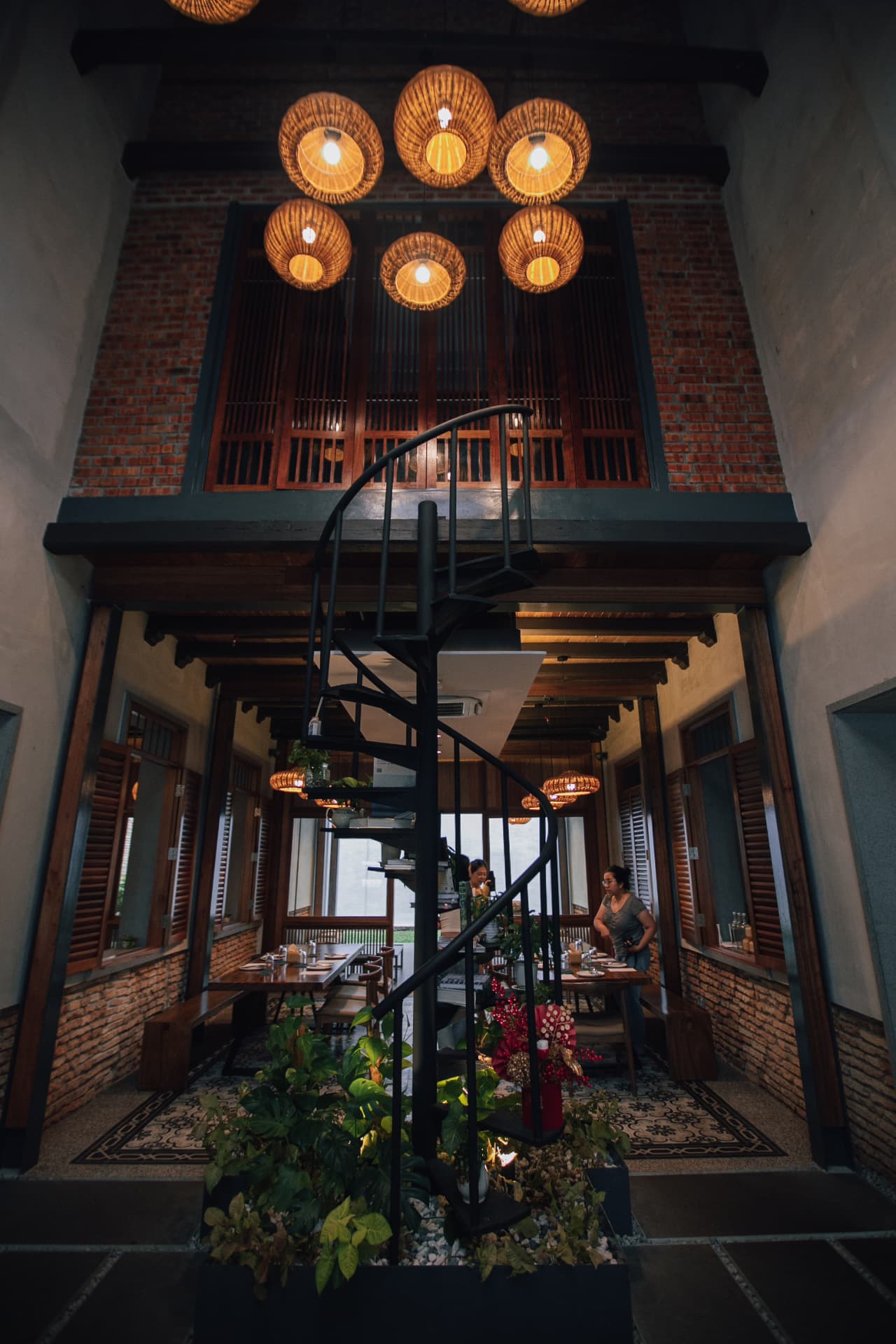 Rumah Kechik's double-height interior with rattan lanterns and spiral staircase